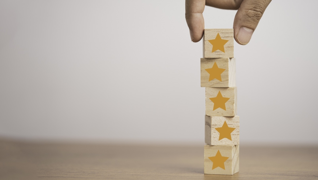 Hand putting yellow stars which print screen on wooden cube block  for customer satisfaction concept.