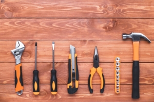 Set of construction tools on a brown wood background. Hammer, wrench, pliers and screwdriver. Frame border, postcard for the holiday Labor Day. Equipment, workplace. Flat design, copy space